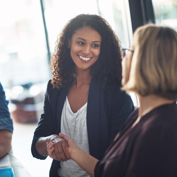 Two businesswomen shaking hands during a meeting in a modern office