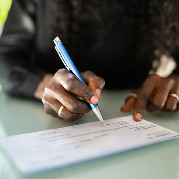 close up view of a woman writing a check on a white table